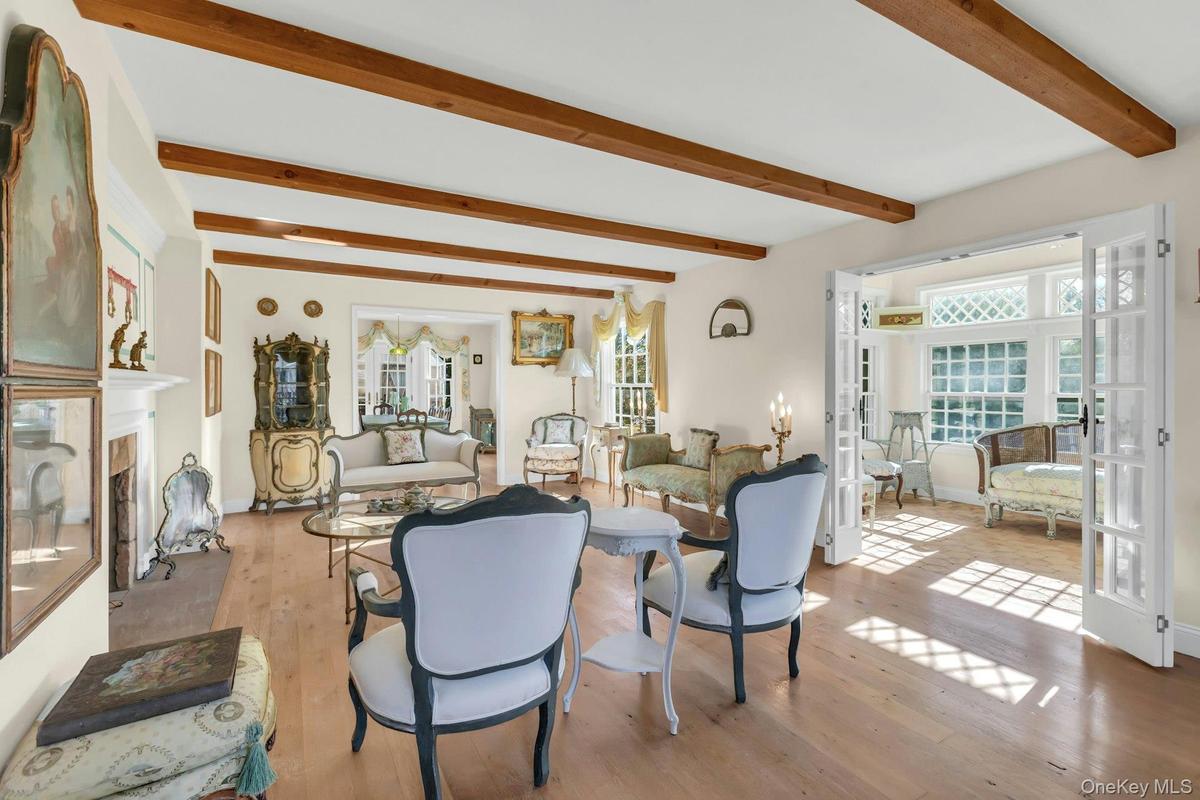Living room with a high end fireplace, french doors, beam ceiling, and light wood finished floors