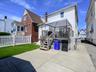 Rear yard featuring a wood deck with stairs, white picket fence, and a grass lawn. ai generated.