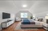 Bedroom with wood finished floors, radiator, and vaulted ceiling