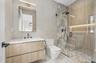 Bathroom featuring a stall shower, vanity, and tile walls