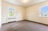 Unfurnished room with radiator heating unit and dark colored carpet