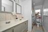 Full bathroom featuring baseboard heating, light tile patterned flooring, a shower with curtain, double vanity, and backsplash