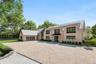 Contemporary home with a garage, gravel driveway, and brick siding