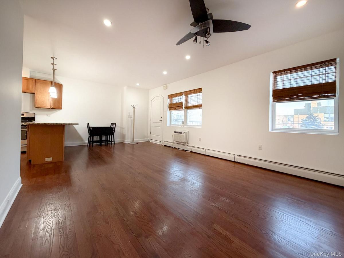 Unfurnished living room featuring a baseboard radiator, recessed lighting, dark wood finished floors, a ceiling fan, and a wall mounted air conditione