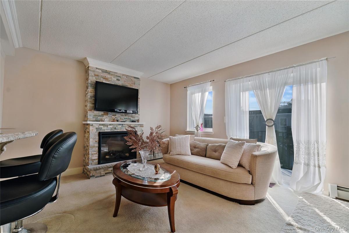 Living area featuring a floor-to-ceiling stacked stone fireplace, an inset electric fireplace, and a wall-mounted television