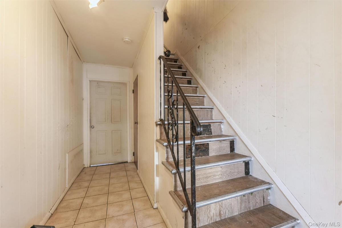 Staircase with tile patterned floors and wood walls