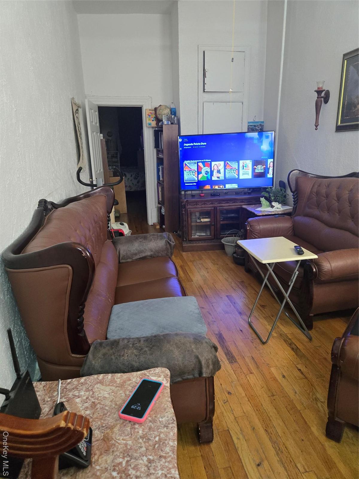 Living room with a textured wall and hardwood / wood-style floors