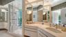 His-and-Her sinks, paired with a glass-enclosed luxury shower featuring dual shower heads
