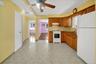 Kitchen featuring wood cabinetry, white appliances, patterned tile flooring, and a ceiling fan with integrated lighting