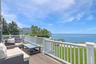 Wooden terrace featuring a water view, a lawn, and outdoor lounge area