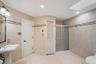 Tiled bathroom featuring a pedestal sink, framed mirror, and a glass-enclosed shower