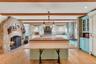 Kitchen with green cabinetry, a fireplace, glass insert cabinets, and beamed ceiling