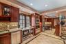 Kitchen featuring inlaid floor details, stainless steel appliances, glass insert cabinets, light stone counters, and recessed lighting
