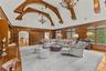 Living area featuring hanging chandeliers, a high ceiling, arched walkways, built in shelves, and rich wood paneled walls.