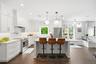 A bright, beautifully updated open-concept kitchen featuring custom white cabinetry, sleek countertops, stainless-steel appliances and a spacious cent
