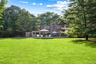 Back of property with a yard, view of wooded area, and a deck
