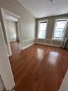 Empty room with light wood-type flooring, radiator, a decorative wall, healthy amount of natural light, and a wainscoted wall