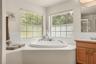 Primary bathroom featuring a soaking tub, oversized windows, and abundant natural light