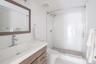 Bathroom with tiled shower, toilet, and vanity
