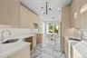 Kitchen with light brown cabinets, modern cabinets, light stone countertops, light marble finish flooring, and a chandelier