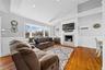 Living room with a wainscoted wall, a decorative wall, wood finished floors, lofted ceiling, and a fireplace with flush hearth