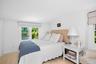 Bright 2nd floor bedroom with wood-finish flooring, white walls, and two windows featuring light-colored Roman shades