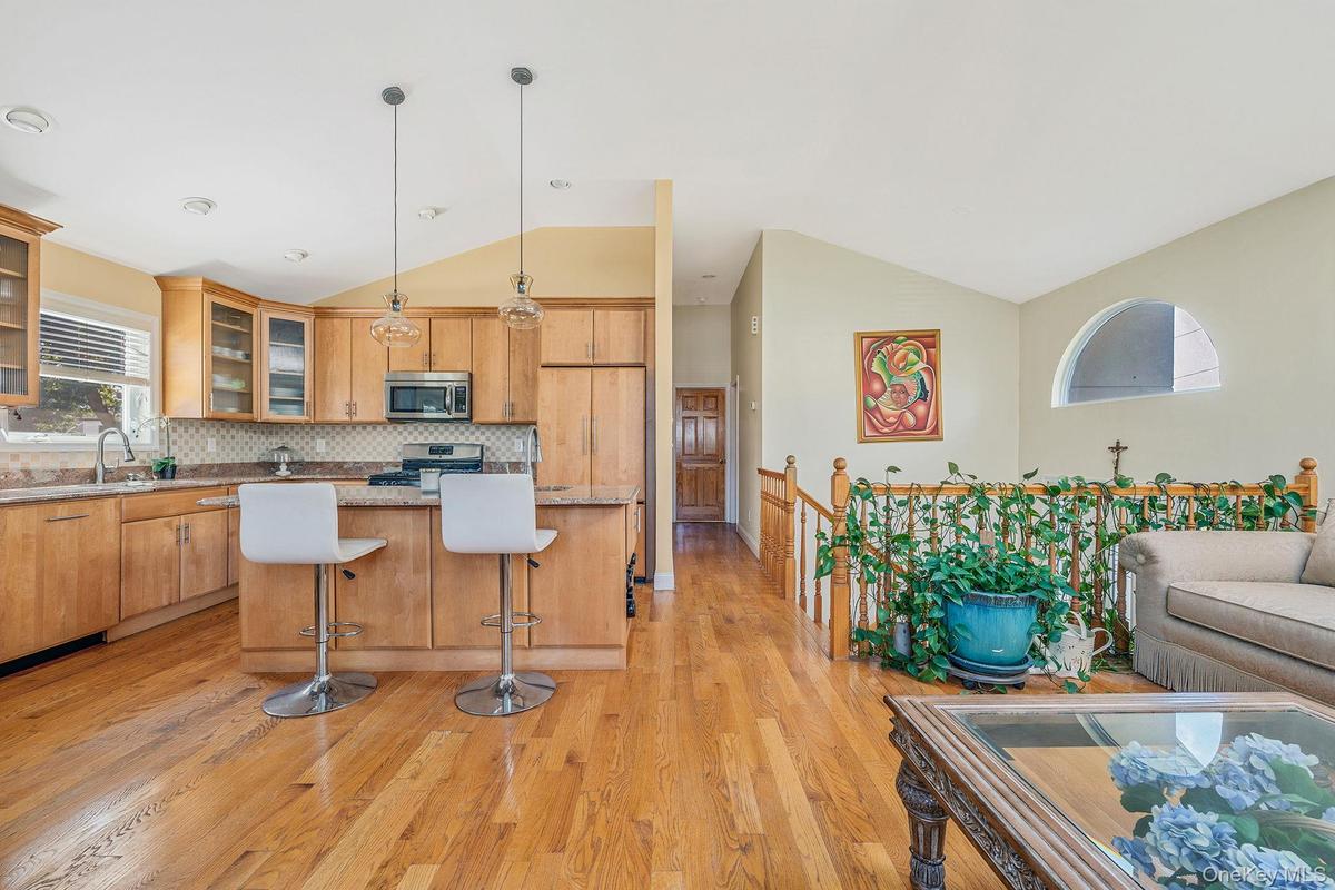 Kitchen with glass insert cabinets, light wood finished floors, open floor plan, a kitchen bar, and pendant lighting