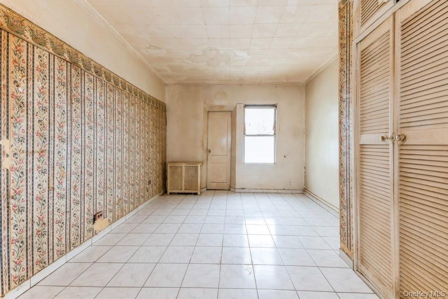 Unfurnished bedroom with crown molding, a closet, and tile patterned floors
