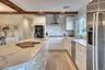 Kitchen featuring wall chimney exhaust hood, a sink, beam ceiling, stainless steel appliances, and backsplash