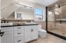 Full bathroom featuring double vanity, a shower stall, and tile walls