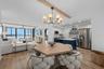 Open-concept great room with engineered hardwood flooring, exposed wood ceiling beam, and seamless flow to the dining area.