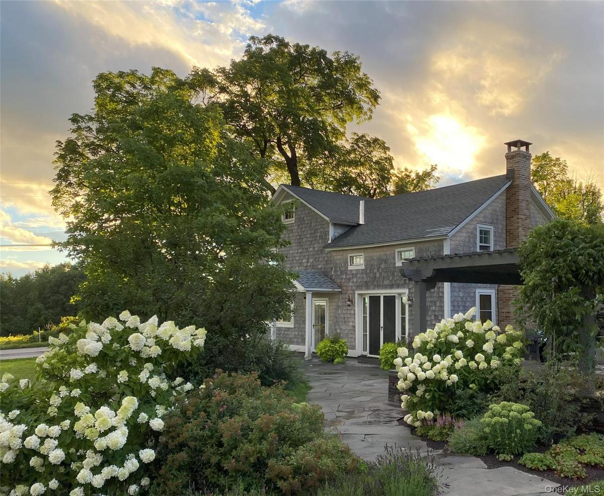 View of front of home featuring a chimney and a shingled roof