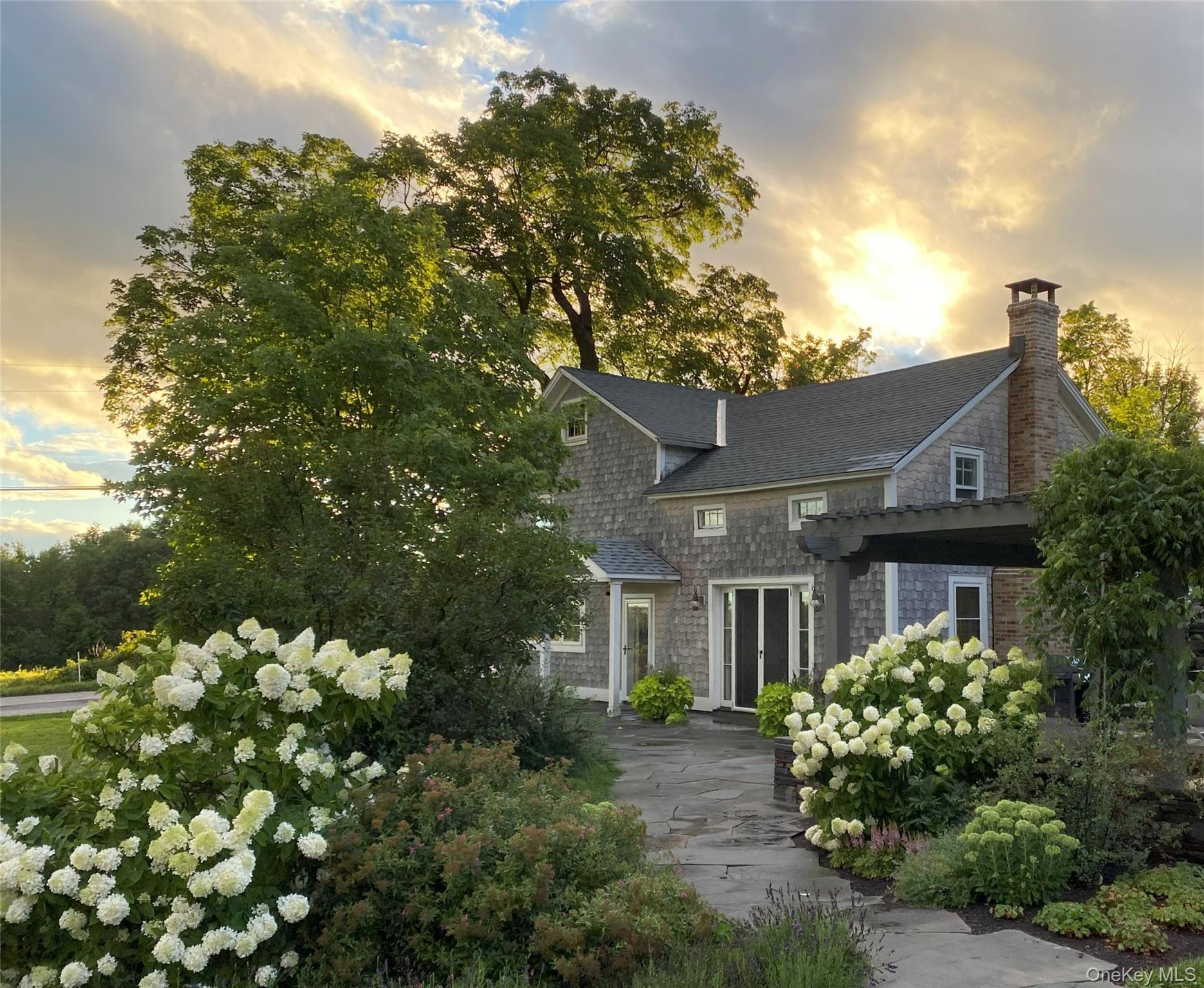 View of front of home featuring a chimney and a shingled roof