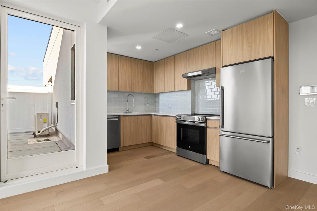 Kitchen with modern cabinets, appliances with stainless steel finishes, tasteful backsplash, light wood-style flooring, and recessed lighting