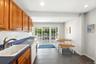 Kitchen featuring wood cabinetry, white subway tile backsplash, dark blue countertops, a built-in sink, & sliding glass door