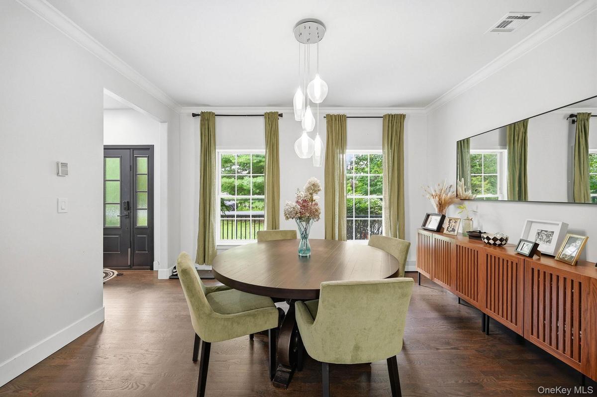 Dining area featuring wood-finish flooring, a contemporary chandelier, crown molding, and multiple windows providing lots of natural light