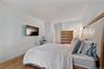 Bedroom featuring wood-finish flooring, a mounted television, a ceiling with textured finish, and light-colored wall paint