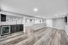 Spacious lower level featuring wood-finish flooring, recessed lighting, and a built-in wet bar with a beverage refrigerator