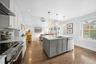 Kitchen with vaulted ceiling, gray cabinets, appliances with stainless steel finishes, open floor plan, and white cabinetry