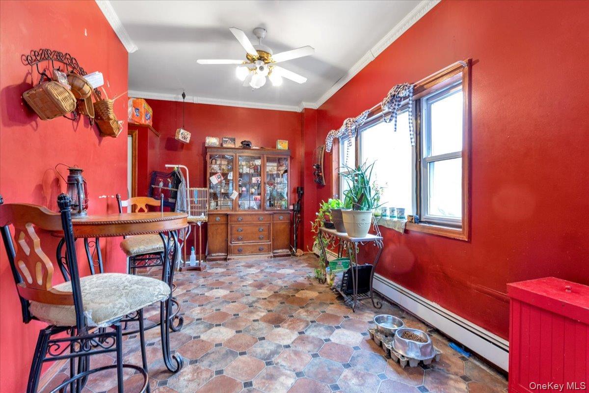 Dining space featuring ceiling fan, a baseboard heating unit, and ornamental molding