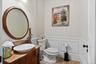 Half bath featuring a decorative wall, vanity, and a wainscoted wall