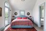 Bedroom with vaulted ceiling, access to outside, multiple windows, and light tile patterned flooring
