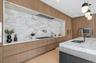 Kitchen with light stone countertops, hanging light fixtures, light wood-style flooring, backsplash, and brown cabinets