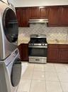 Kitchen featuring stainless steel range with gas stovetop, light tile patterned floors, decorative backsplash, under cabinet range hood, and dark brow