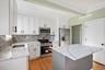 Kitchen featuring stainless steel appliances, white cabinets, a center island, light stone counters, and ornamental molding