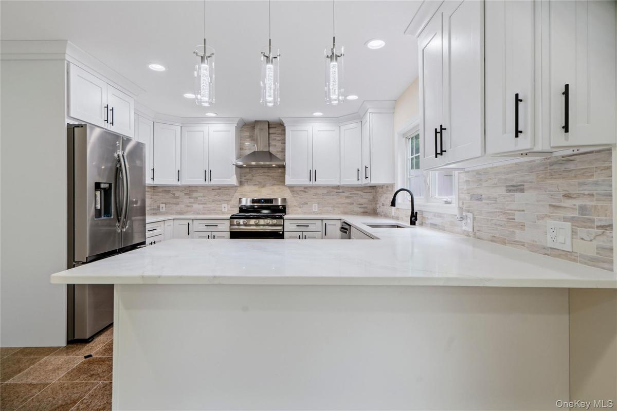 White kitchen featuring a U-shaped layout, quartz countertops, and a full tile backsplash