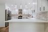 White kitchen featuring a U-shaped layout, quartz countertops, and a full tile backsplash