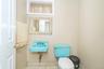 Bathroom featuring a wall-mounted blue basin, matching blue toilet, an ornate framed mirror, and a small recessed window