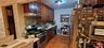 Kitchen featuring stainless steel appliances, tasteful backsplash, light wood-style floors, under cabinet range hood, and dark brown cabinetry