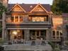 Back of property featuring a standing seam roof, a metal roof, stone siding, and a balcony